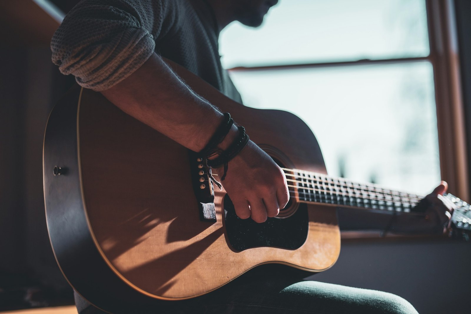 Musician playing an acoustic guitar in warm light